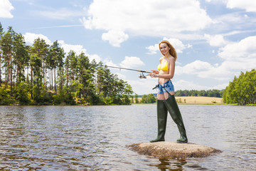 young woman fishing in pond during summer