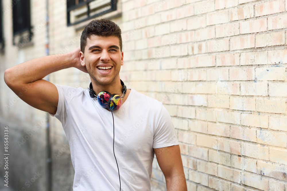 Poster Young man in urban background listening to music with headphones