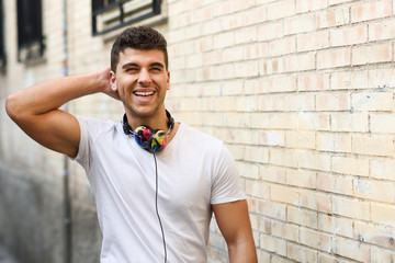 Young man in urban background listening to music with headphones