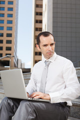 Business man sitting on steps using laptop