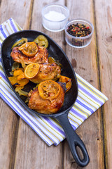 Delicious baked chicken thighs with lemon slices, onion and zucchini 