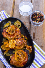 Delicious baked chicken thighs with lemon slices, onion and zucchini 