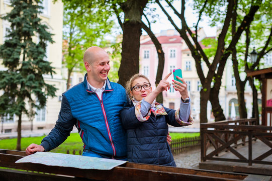 Young fashion elegant stylish couple, travel by old European cities, looking way on the map, smile, selphi