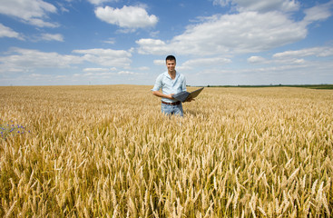 Naklejka na ściany i meble Farmer with laptop in wheat field