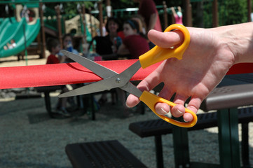 Hand and scissors cutting a ribbon during an opening ceremony