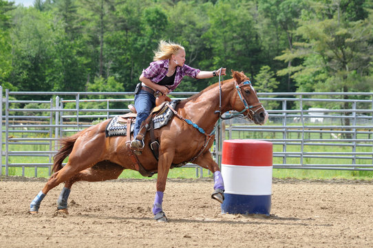 Young adult woman galloping around a turn in a barrel race