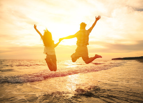 young happy couple jumping on beach