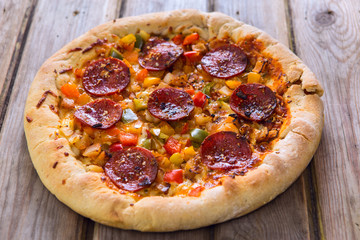 Delicious baked salami pizza served on rustic wooden table