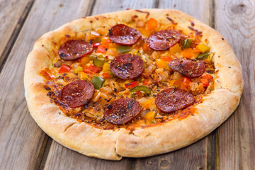 Delicious baked salami pizza served on rustic wooden table