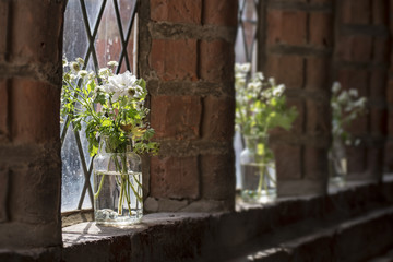 Fototapeta premium white meadow flowers in the windows of an old monastery