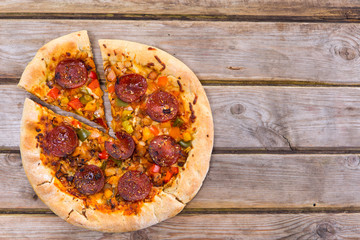 Delicious baked salami pizza served on rustic wooden table