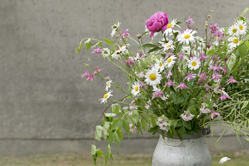 rural bouquet with pink and white flowers in front of a gray wal
