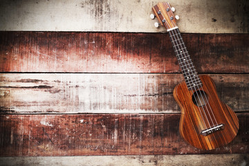 Vintage ukulele on wooden background.