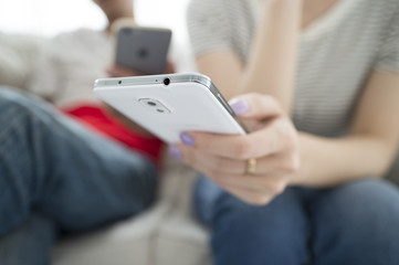 Couples using a smart phone on the sofa