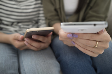 Women looking at smart phone sitting on the sofa