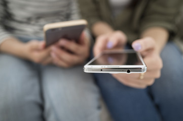 Women looking at smart phone sitting on the sofa