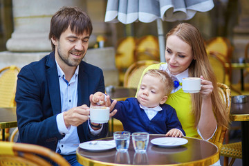 Happy family of three in Parisian cafe