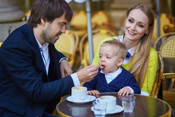 Happy family of three in Parisian cafe