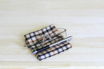Glasses, pen and a plaid handkerchief
