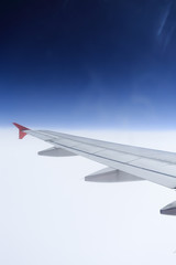 Wing of an airplane flying above the clouds.