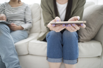 Women looking at smart phone sitting on the sofa
