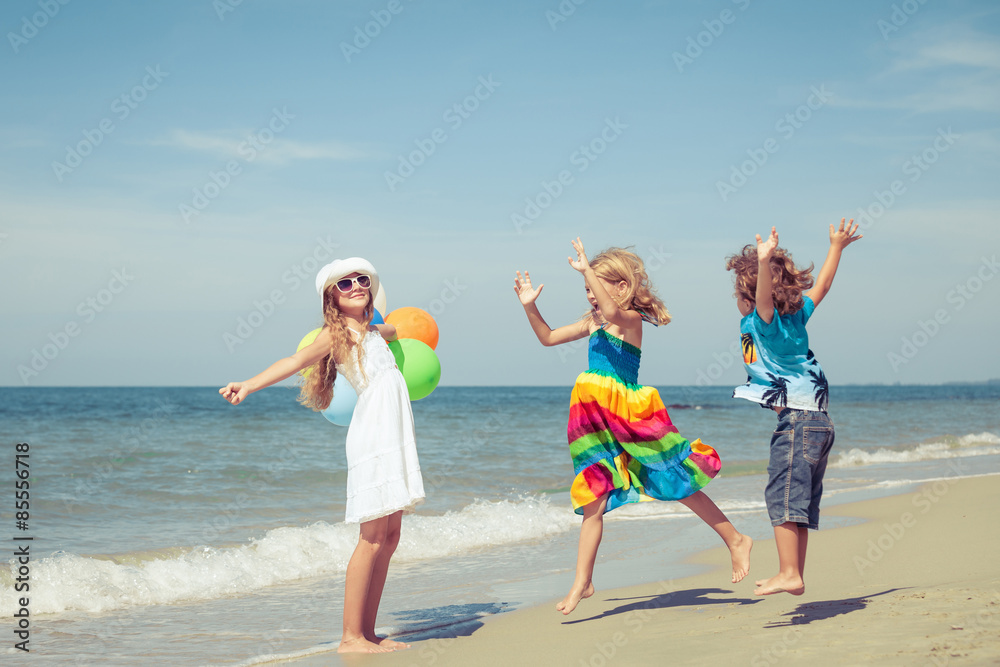 Sticker Three happy children with balloons  dancing on the beach