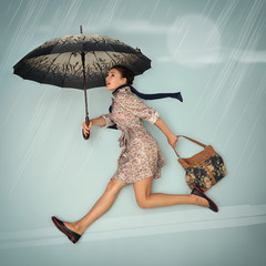 Young woman running hurry up holding umbrella and bag in the aut
