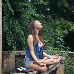 Happy yoga girl ralaxing in city park in lotus position. Outdoor