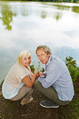 Paar Senioren hockt am Ufer vom See