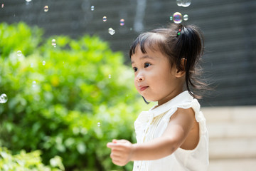 Asian baby girl play bubble blower at outdoor