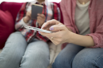 Obraz premium Two women looking at a smart phone on the sofa