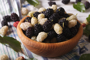 Fresh white and black mulberries in a wooden bowl