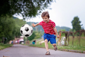 Two cute little kids, playing football together, summertime