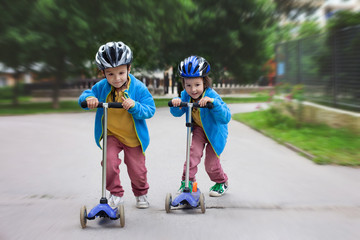 Two cute boys, compete in riding scooters, outdoor in the park © Tomsickova