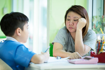 Serious Asian Mother Helping Son With Homework