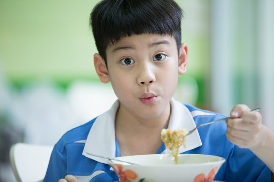 Young Chinese Boy Sitting At Home Eating Meal