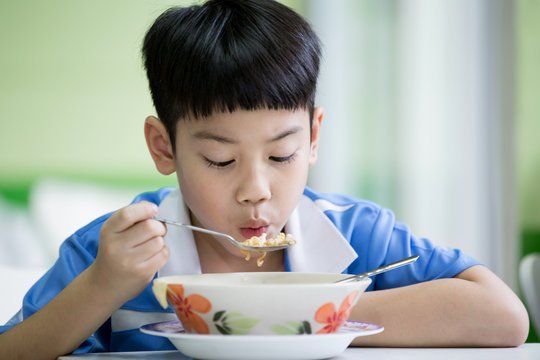 Young Chinese Boy Sitting At Home Eating Meal