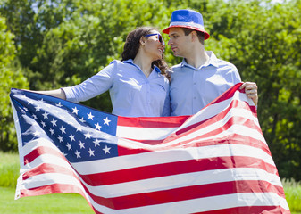 Cheerful couple with American flag for july 4th while patriotic holiday 