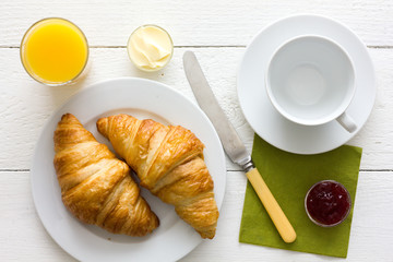 Coffee, orange juice and croissant breakfast, empty cup. From above.