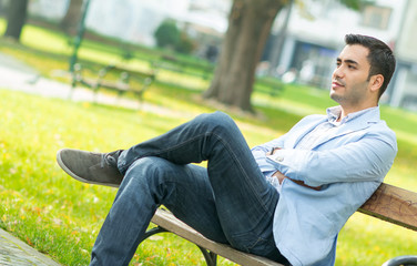 Fototapeta premium Serious man sitting on bench in a park