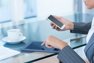Fototapeta premium Businesswoman using smartphone and tablet
