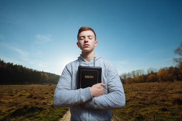 Young man holding Bible in a park