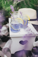 Homemade lavender lemonade with fresh lemons on a white wooden tray in a lavender field
