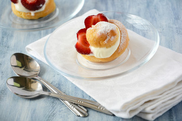Homemade eclairs with strawberries on dark wooden background