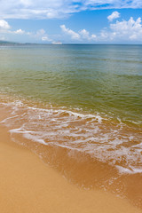 Beach on tropical island. Clear blue water, sand, clouds. 