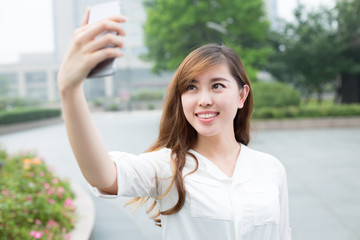 asian beautiful young woman using mobile phone to take selfie ou