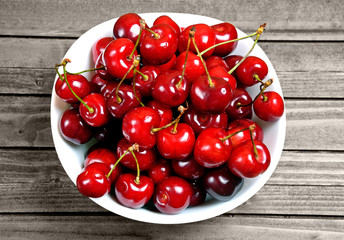 Bowl with cherries on wooden table