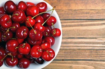 Bowl with cherries on wooden table