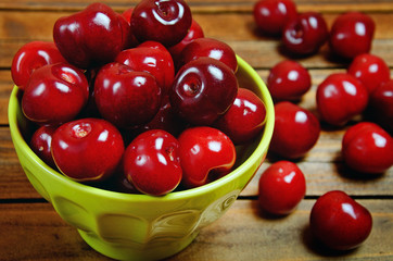 Green bowl with cherries on table