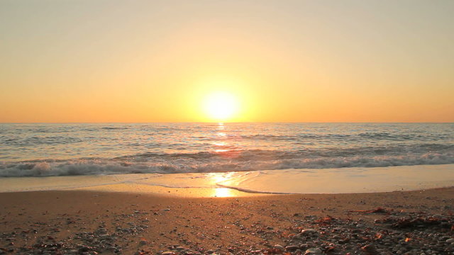 Sunset on the beach - Tranquil idyllic scene of a golden sunset over the sea, waves slowly splashing on the sand